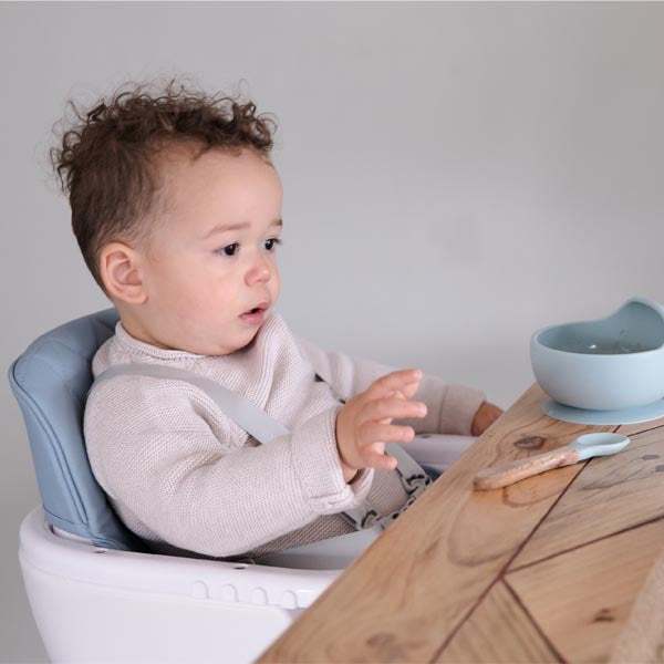 baby High Chair with a pale blue-grey padded seat and white tray, holding a toddler secured by a harness